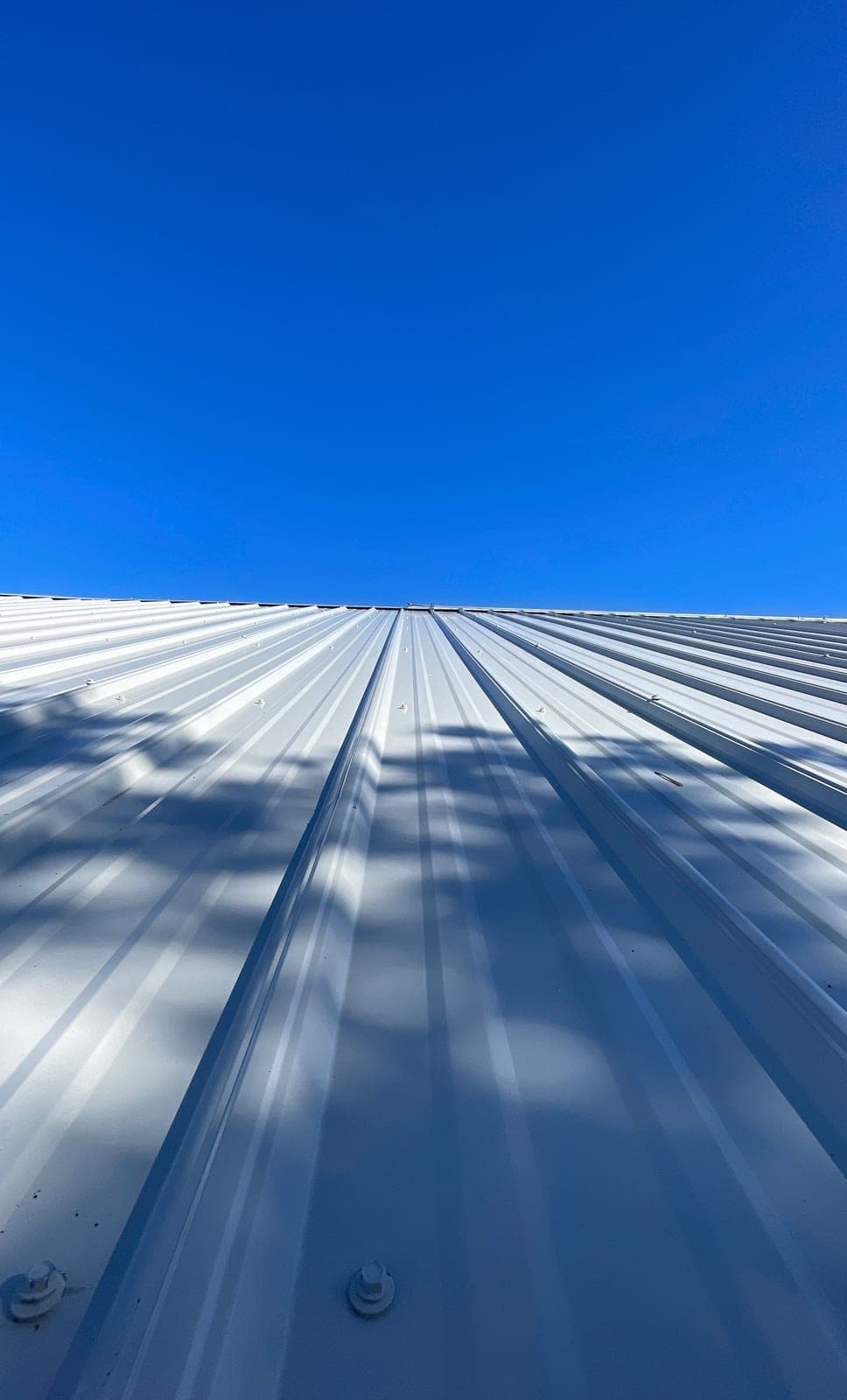 A finished gray R-panel metal roof under a blue New Mexico sky by Paramount Roofing