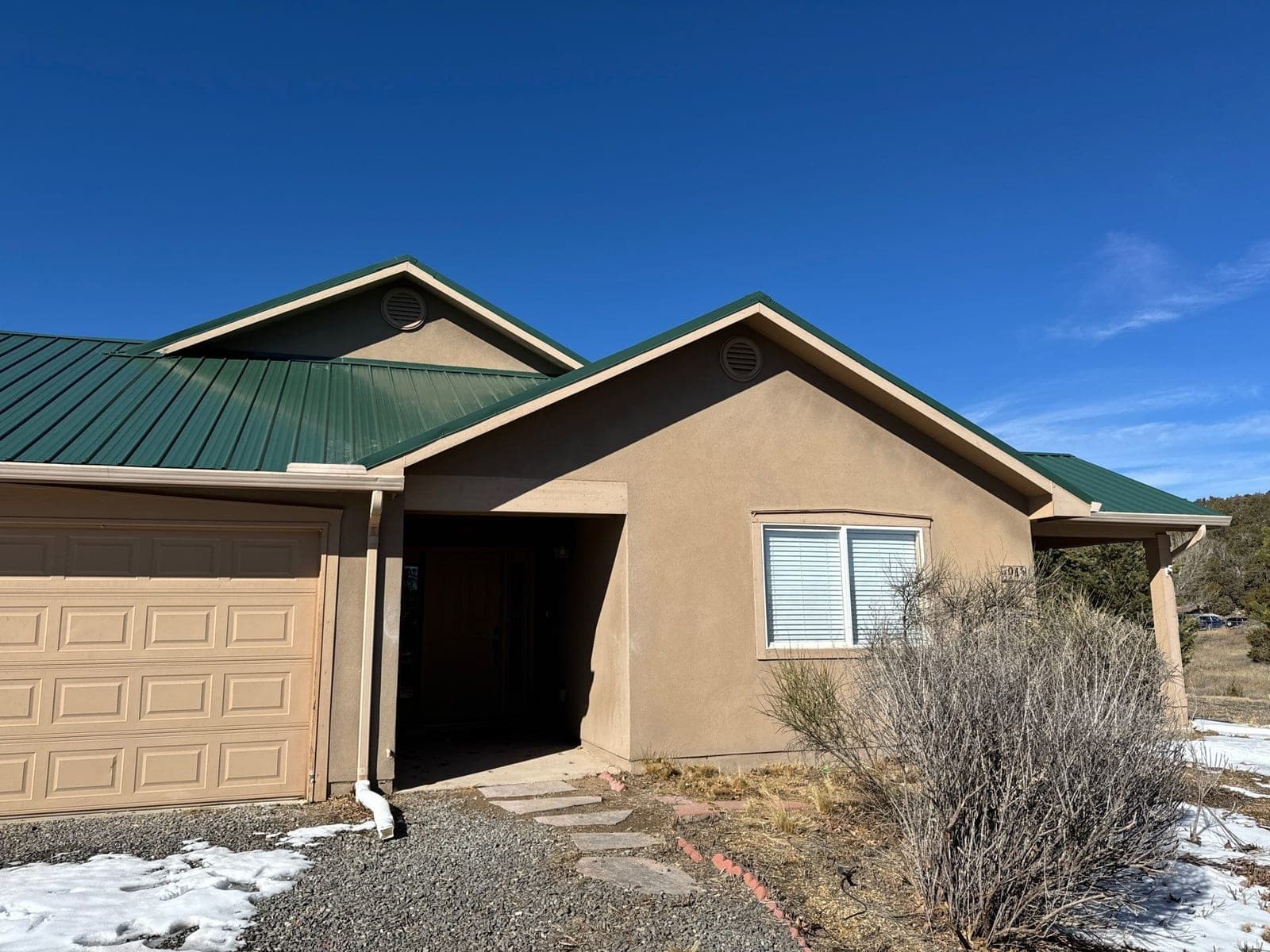 A finished green metal roof on a New Mexico home, the kind included in a Paramount Care Roof Health Report