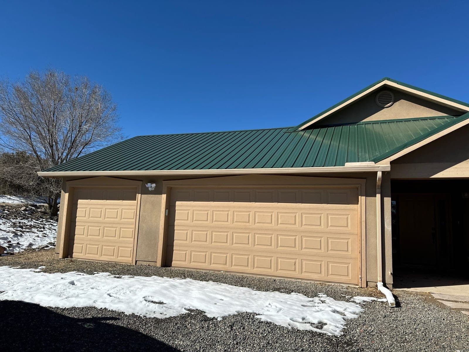 A finished green metal roof on a New Mexico stucco home and garage by Paramount Roofing