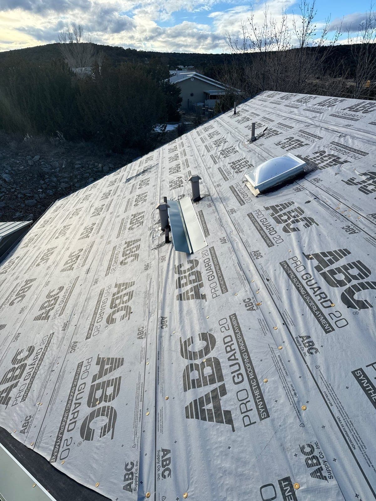 A metal roof deck with underlayment around a skylight opening by Paramount Roofing in New Mexico