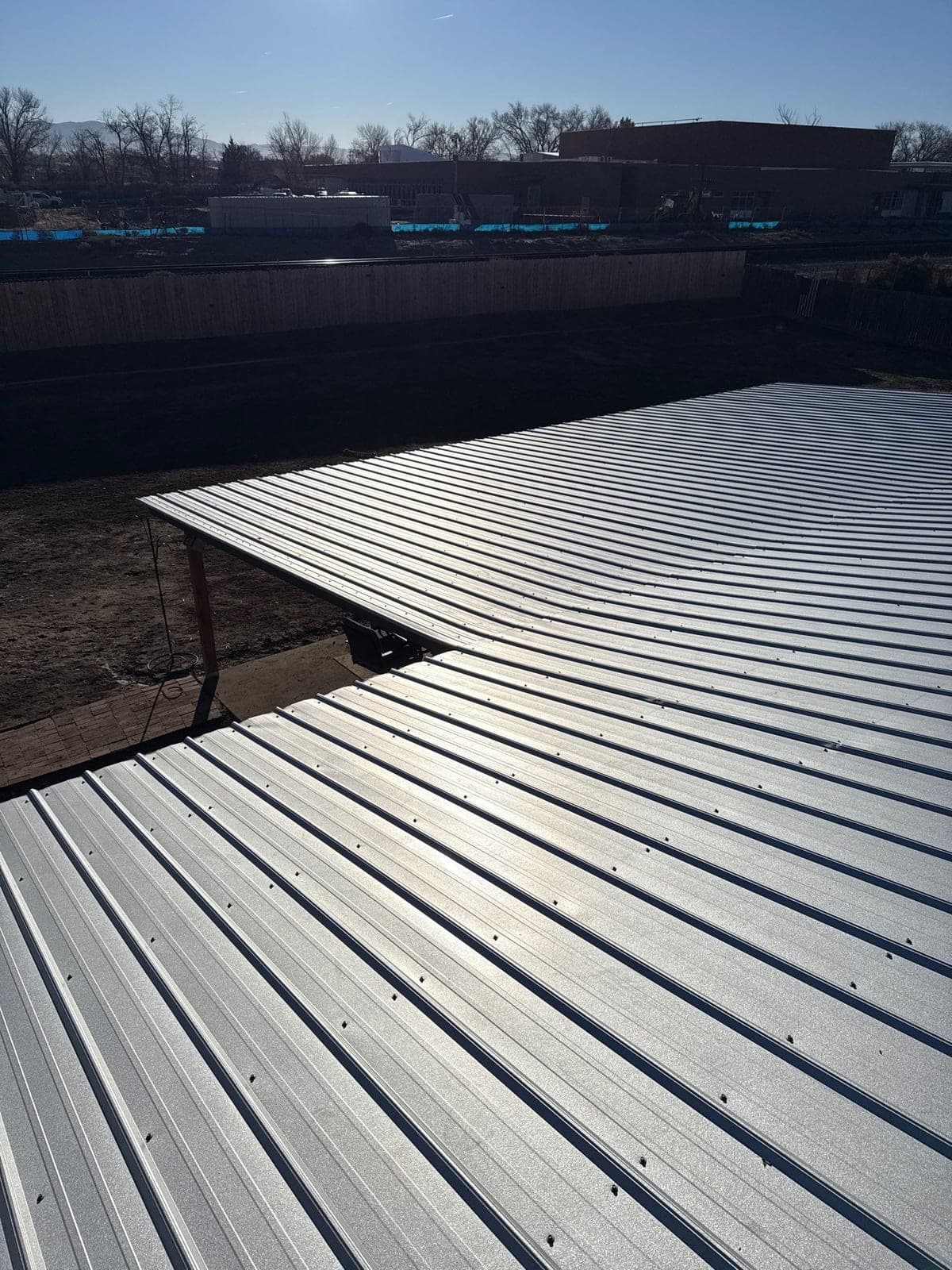 A finished silver R-panel metal roof on a low-slope New Mexico home by Paramount Roofing