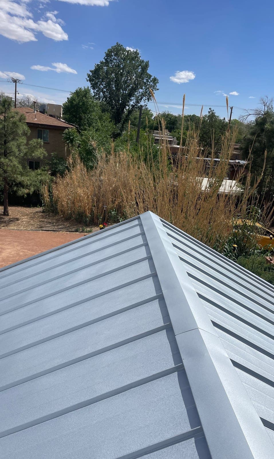 A close-up of a finished silver standing-seam metal roof by Paramount Roofing in New Mexico