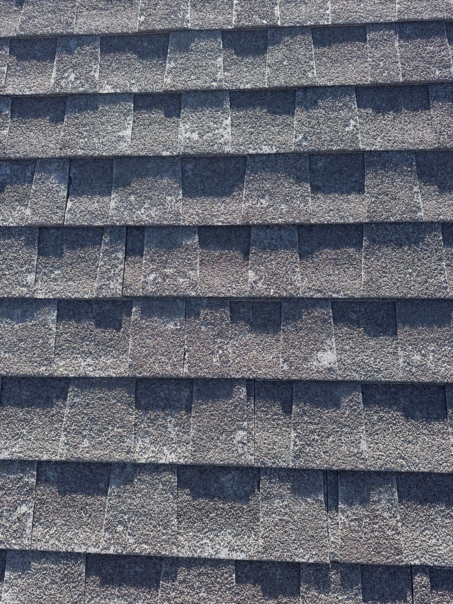 Close-up of a weathered, sun-aged asphalt shingle roof at the repair-or-replace decision point