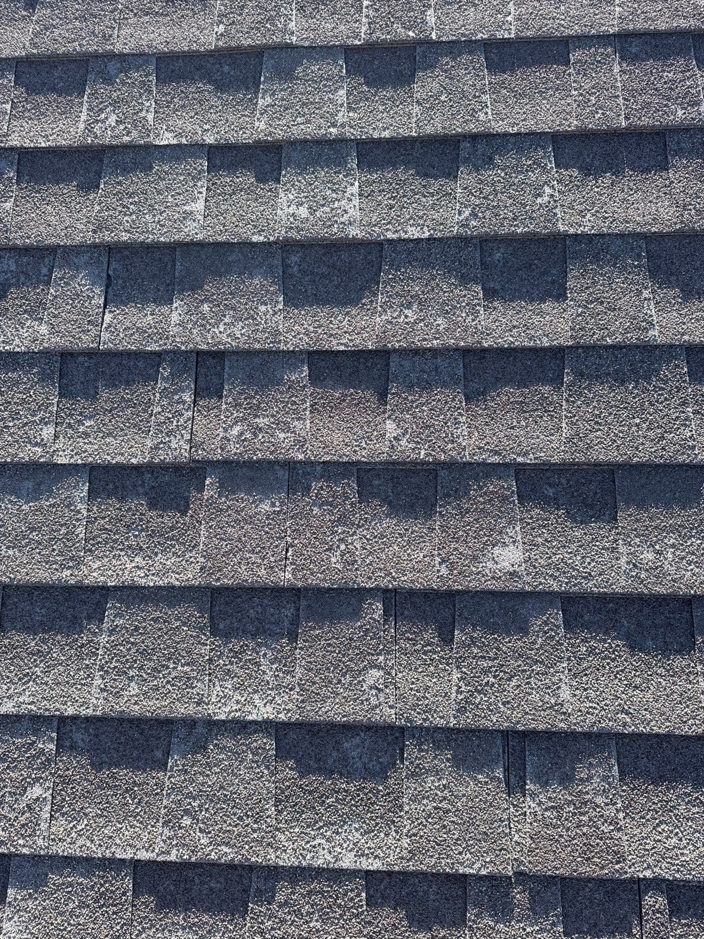 Close-up of a weathered, sun-aged asphalt shingle roof at the repair-or-replace decision point