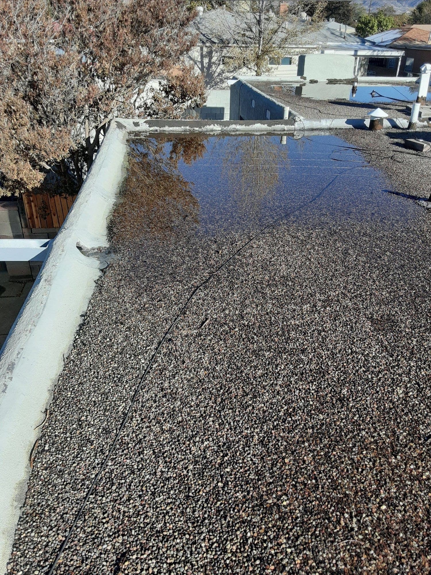 Ponding water collecting in a low spot on a low-slope gravel roof
