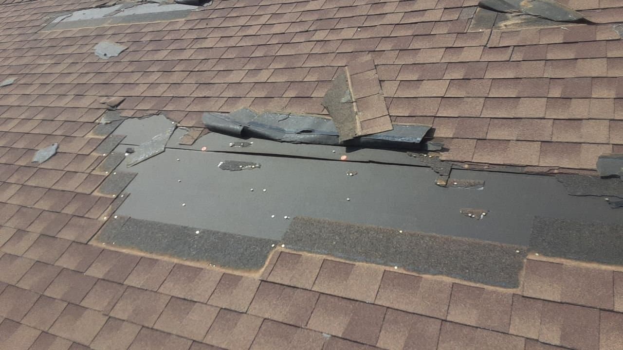 Asphalt shingles torn loose and lifted by storm wind on a New Mexico roof, documented by Paramount Roofing