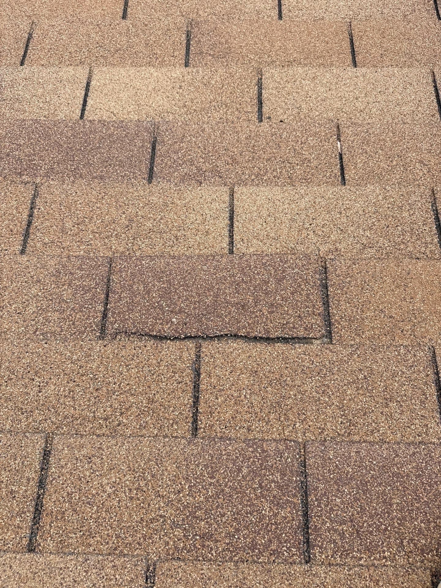 Curling and lifted asphalt shingles across an aging roof surface