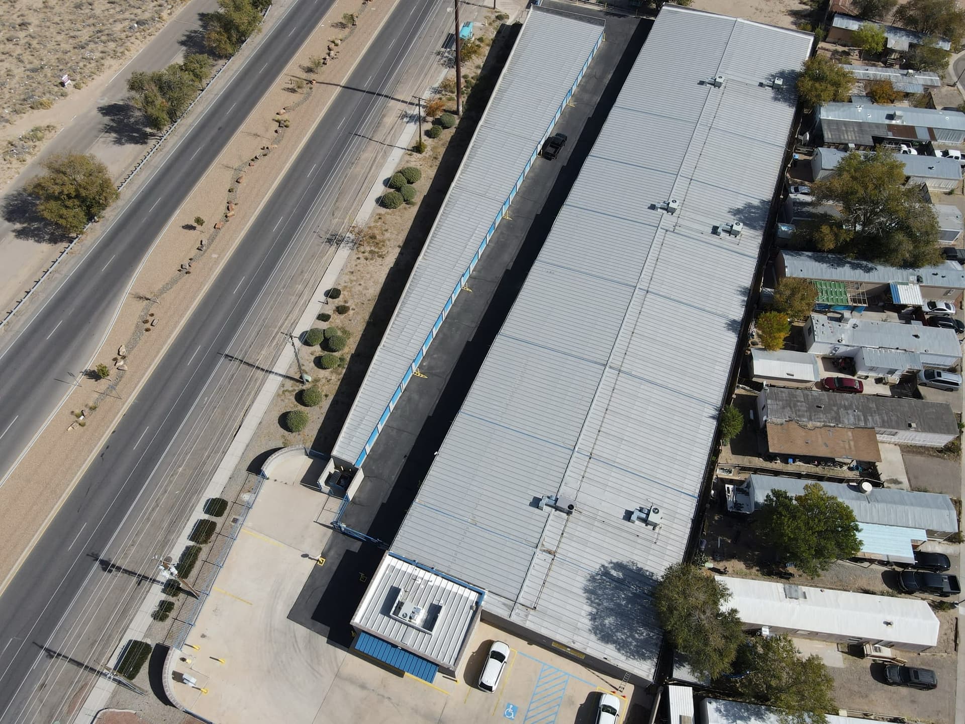 Aerial view of a long commercial metal roof beside a New Mexico highway, documented by Paramount Roofing