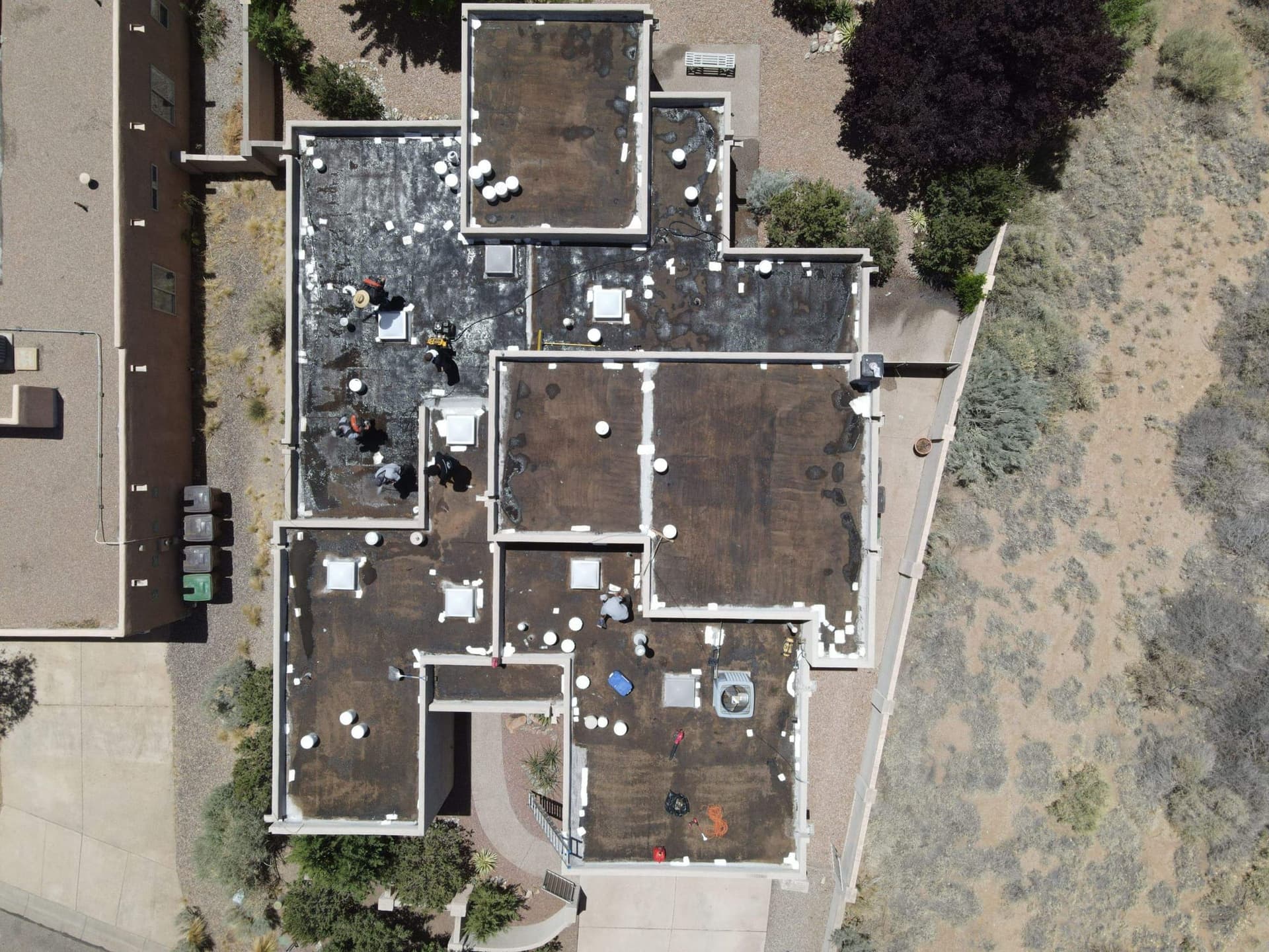 Overhead drone view of a Paramount Roofing crew documenting and servicing a flat roof on a New Mexico home
