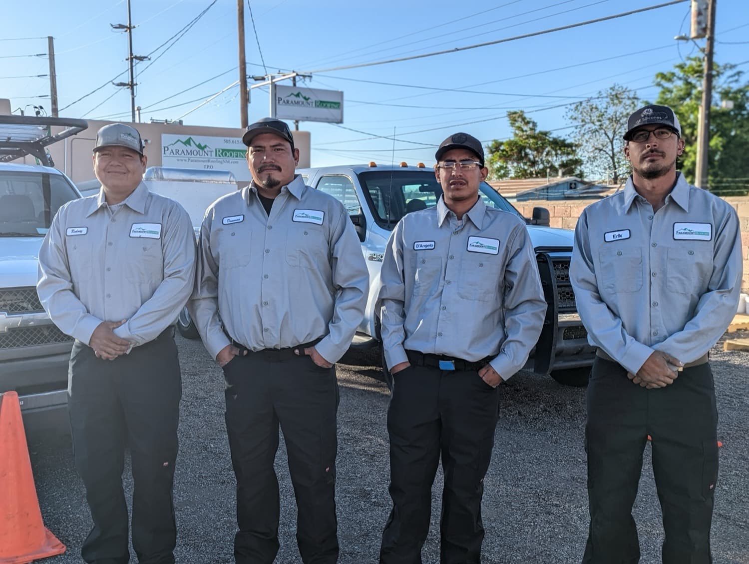 The Paramount Roofing crew in uniform in front of the company trucks