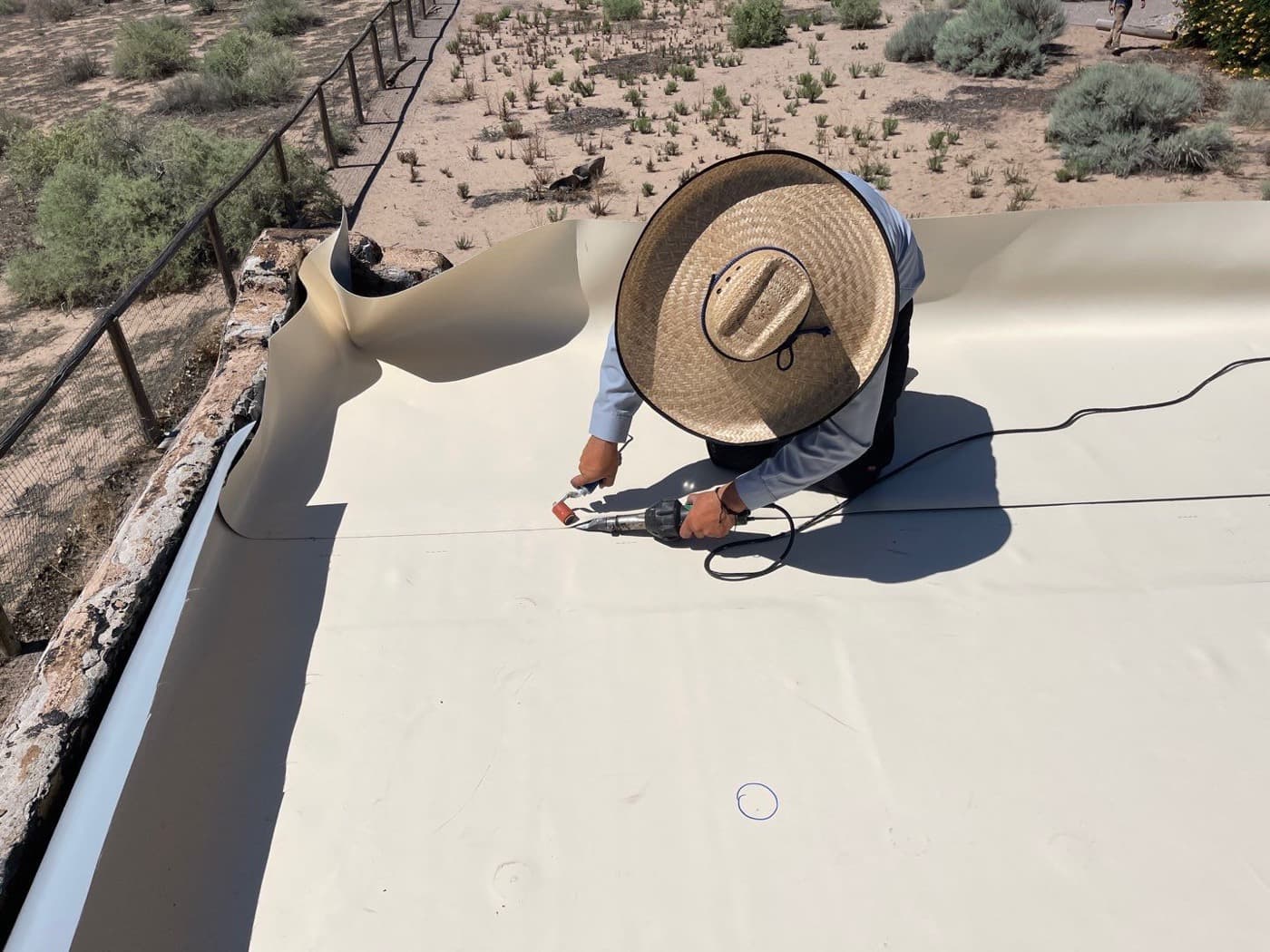 A Paramount Roofing technician inspecting and re-sealing a flat roof during a Paramount Care visit
