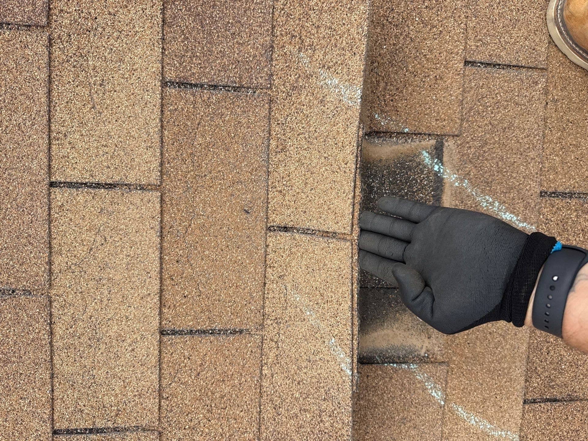 A Paramount Roofing inspector marking shingle damage by hand during a pre-listing roof inspection on a New Mexico home