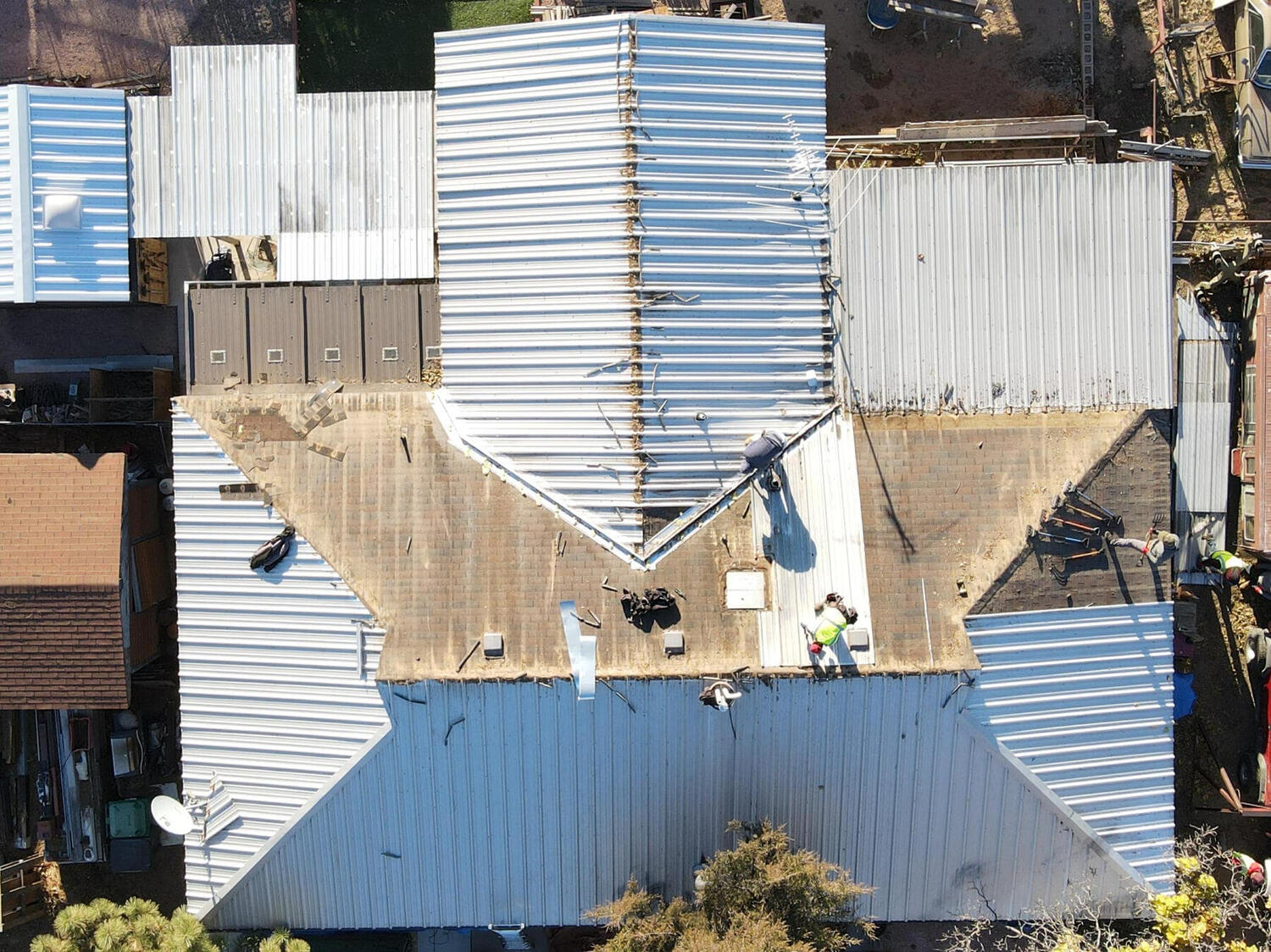 Drone view from above capturing the process of a metal roof being removed and replaced with a new metal roof on a building in Albuquerque.